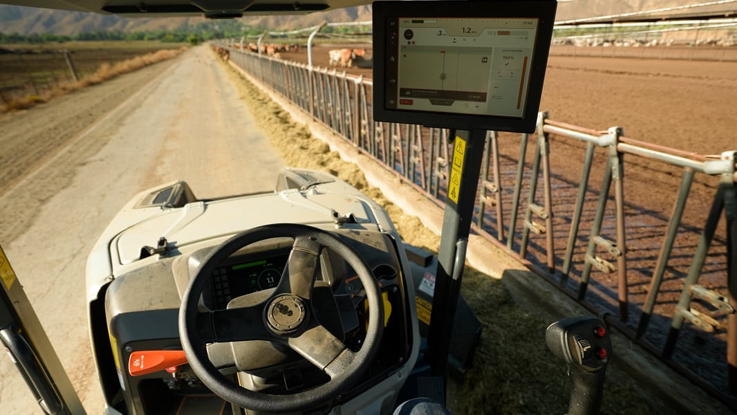 Front seat perspective of driverless tractor on a dusty dairy lane.