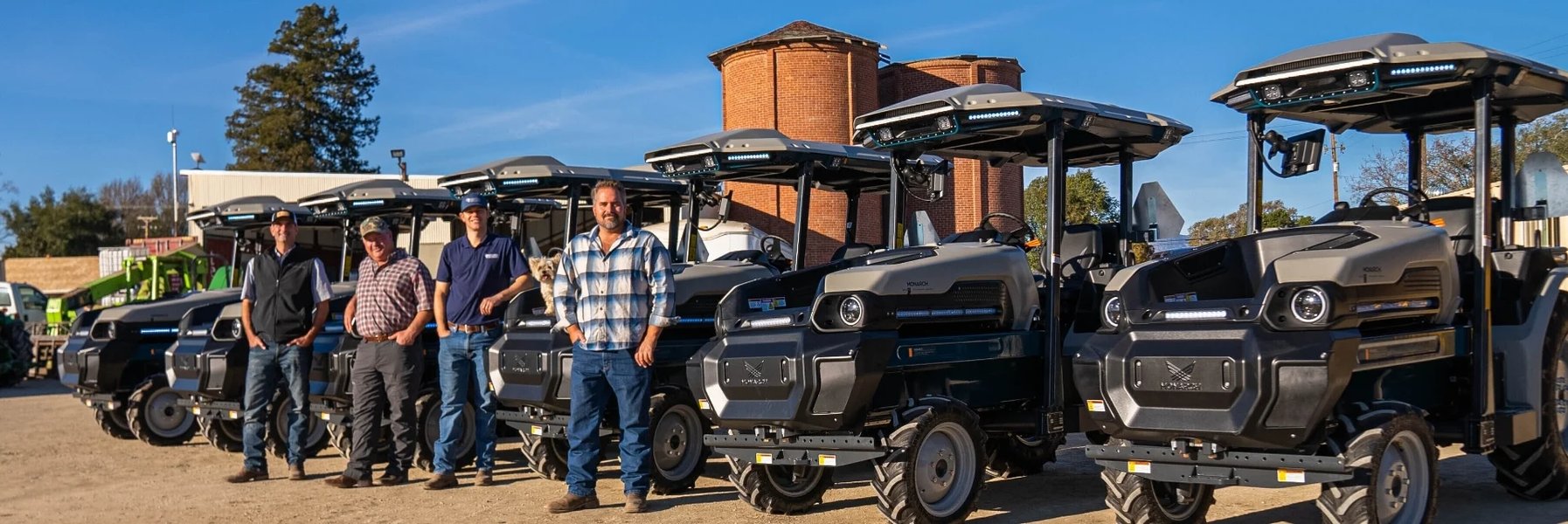 six electric monarch mkv tractors with a group of farmers standing in front of them